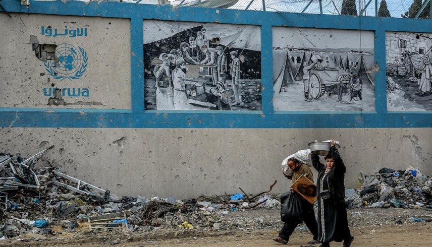 فلسطينيان أمام مبنى مدمر لأونروا في غزة (أرشيف)
