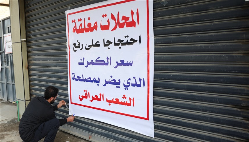 عراقي يعلق لافتة احتجاجية على باب محله التجاري في بغداد (أرشيف)